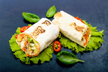 Shawarma - Middle Eastern dish made from lavash (pita), stuffed with chicken, mushrooms, fresh vegetable salad, sauce. Serving on lettuce leaves on a light background. The top view.