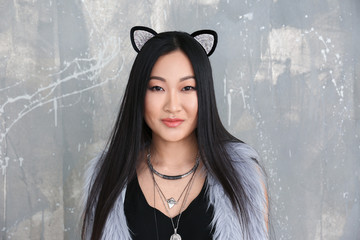 Young woman in cat ears on color background