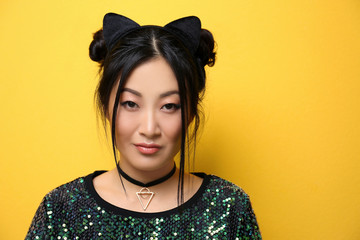 Young woman in cat ears on color background