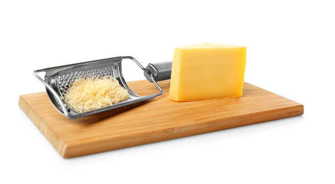 Wooden board with grater and piece of cheese on white background