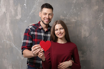 Obraz na płótnie Canvas Happy young couple with red heart on grunge background