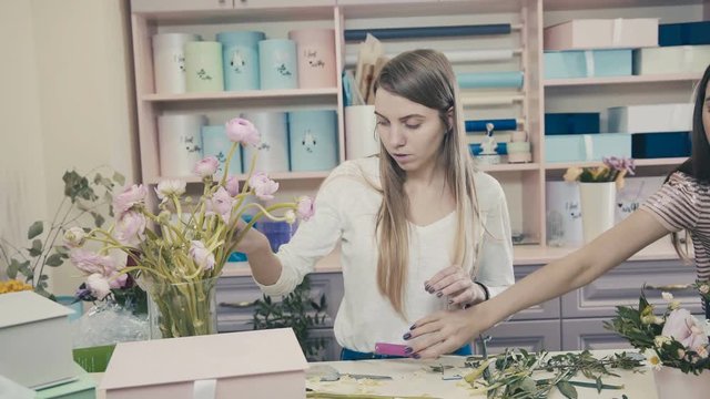 Female florist in flower shop. Floral design studio, making decorations and arrangements. Florist. Flower shop. Drawing up bouquets. Flowers in a hat box. Fashionable flower arrangement.