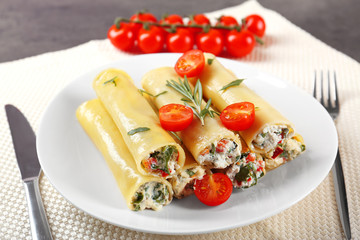 Delicious stuffed cannelloni with cherry tomatoes on plate