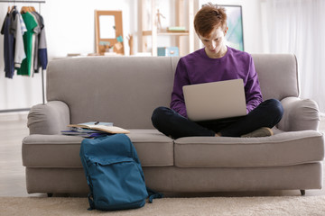 Teenager working with laptop at home