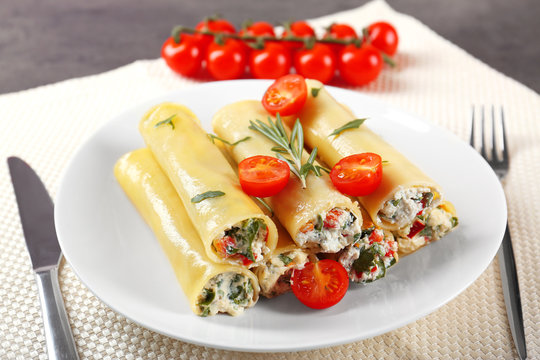 Delicious stuffed cannelloni with cherry tomatoes on plate