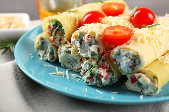 Delicious stuffed cannelloni with cherry tomatoes on blue plate
