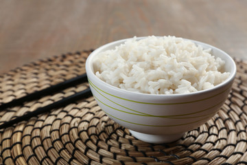 Bowl of rice and chopsticks on wicker mat