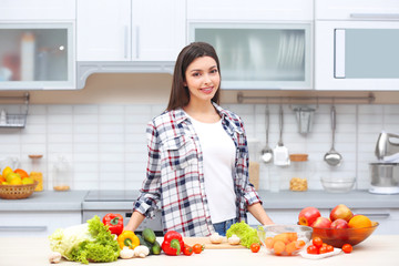 Beautiful young woman with fresh products in kitchen