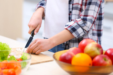 Young woman cutting products on kitchen table