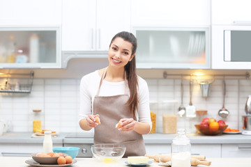 Beautiful young woman cooking in kitchen