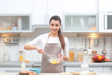 Beautiful young woman cooking in kitchen