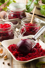 Grated beetroot marinated in jars. Wooden background.