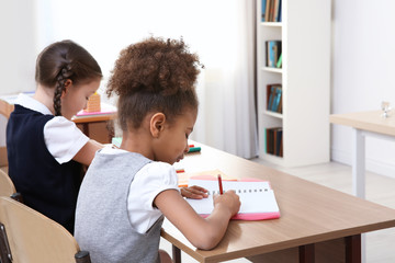 Beautiful elementary schoolgirls studying in classroom