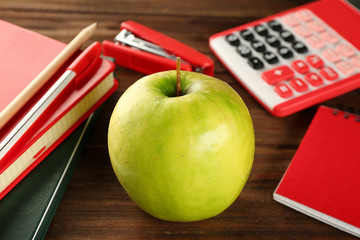 Appetizing green apple and stationery on wooden background