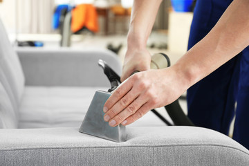 Dry cleaner's employee removing dirt from furniture in flat, closeup