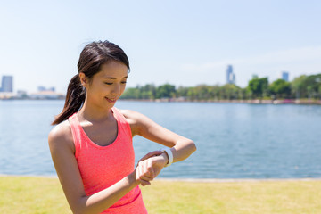 Fototapeta na wymiar Woman using smart watch when running in park