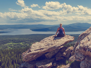 Fototapeta premium The girl sits back on top of the mountain