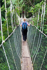 Fototapeta premium woman with backpack walks the longest suspension rope bridge in the world in Malaysia. travel and adventure concept.