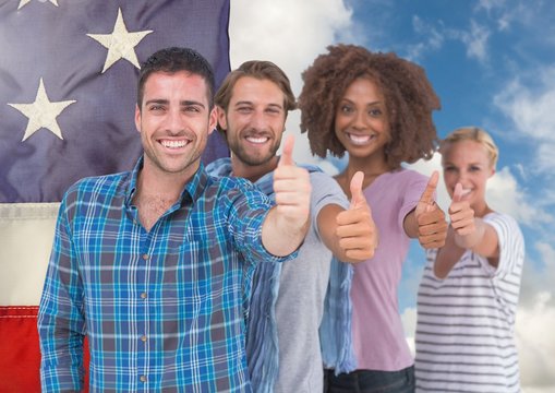 Colleagues showing thumbs up against american flag in sky