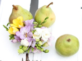 Three pear and freesia flowers, under exposed, on vintage wooden crate 