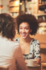 Mixed race woman in coffee shop having coffee and smiling