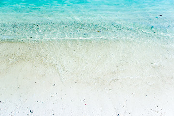 Fototapeta na wymiar white sand with blue green waves on the beach