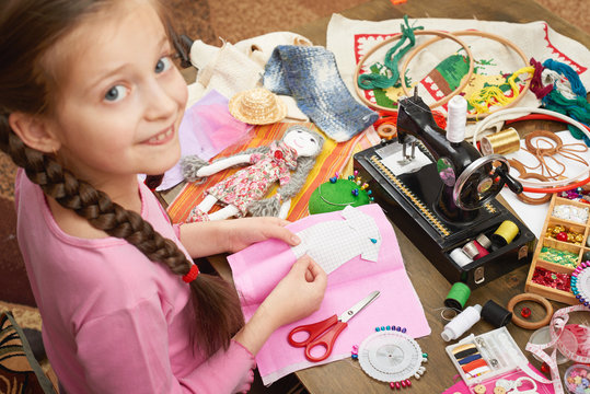 girl sews doll clothes, top view, sewing accessories top view, seamstress workplace, many object for needlework, handmade and handicraft