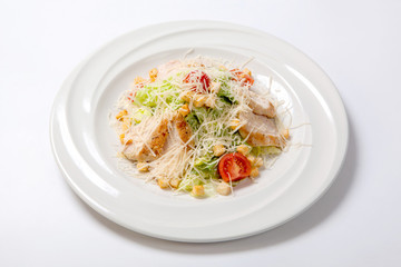 Caesar salad with chicken on a white round plate