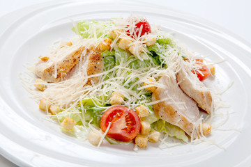 Caesar salad with chicken on a white round plate