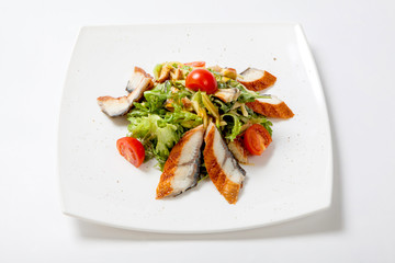 Salad lettuce with pieces of grilled fish, tomatoes and grated cheese