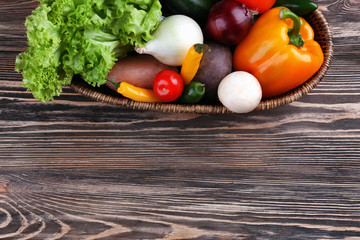 Fresh vegetables in basket on wooden table