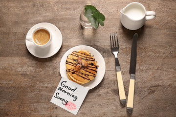 Delicious breakfast and GOOD MORNING greeting note on wooden table, top view
