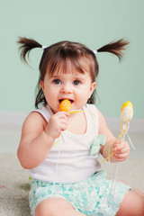 vertical close up indoor portrait of cute happy baby girl playing with easter decorations