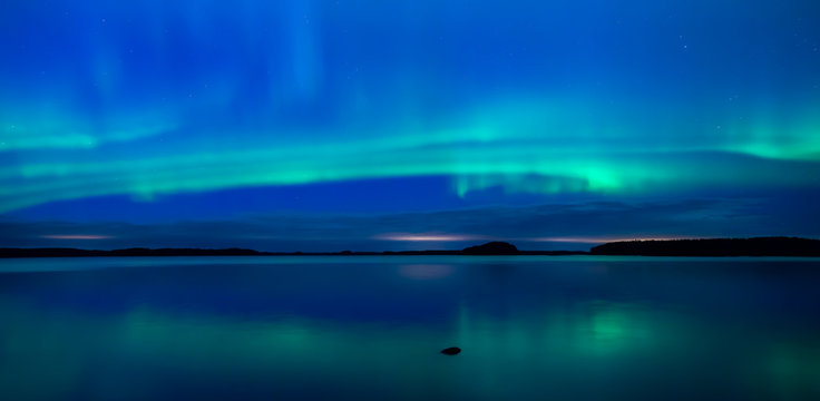 Northern lights dancing over calm lake (Aurora borealis)