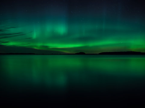 Northern lights dancing over calm lake (Aurora borealis)
