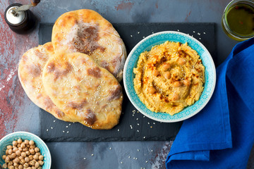 Hummus, chickpeas, with spices and pita, flat cake in a plate on a background of gray stone. Selective focus.