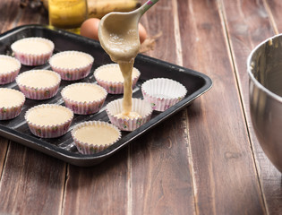 Pouring banana cake into preparing cupcakes.