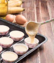 Pouring banana cake into preparing cupcakes.