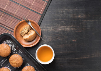 banana cup cake in a baking tray and tea on wood,top view