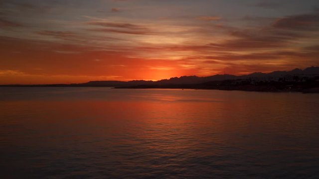 Shoreline at sunset. On the horizon there are mountains