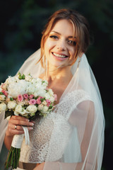 Naklejka premium Blonde bride smiles tender standing in the rays of evening light