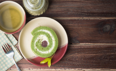 Green tea cake roll and hot green tea matcha on wood background,top view