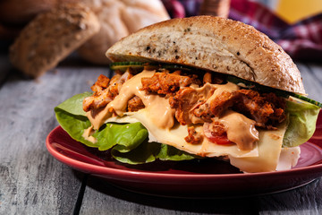 Fried chicken meat with cheese and vegetables in bun