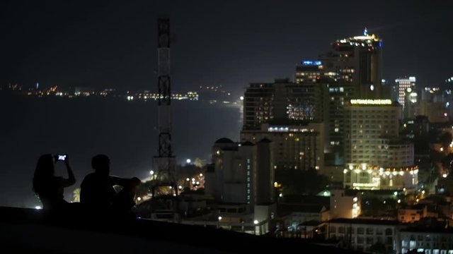 Man and woman sitting on the roof of the building at night