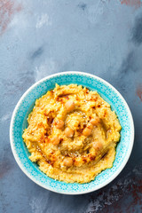 Hummus, chickpeas, with spices and pita, flat cake in a plate on a background of gray stone. Selective focus.