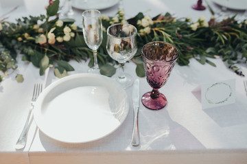 Festive table served dishes and decorated with branches of greenery, stands on green grass in the area of wedding party