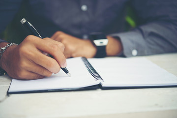 Young man hands writing on book in office.Businessman working on desk of wood.Business.