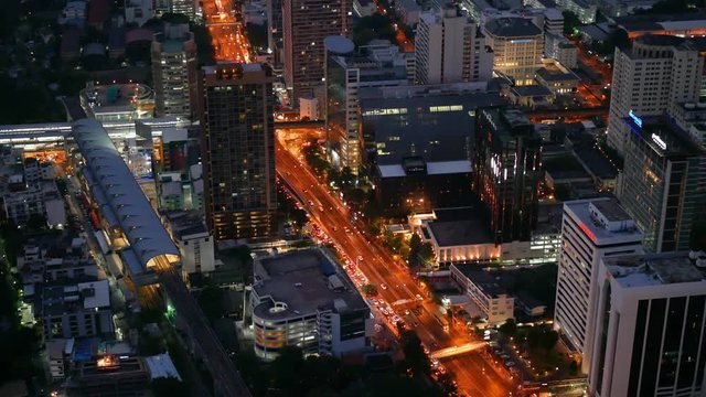 Aerial night vertical view of skyscraper rooftops and illuminated streets in a modern city