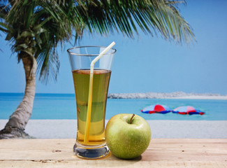 Glass of apple juice on a beach table