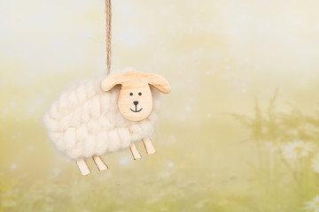 Wooden and woll decoration sheep on a green spring background